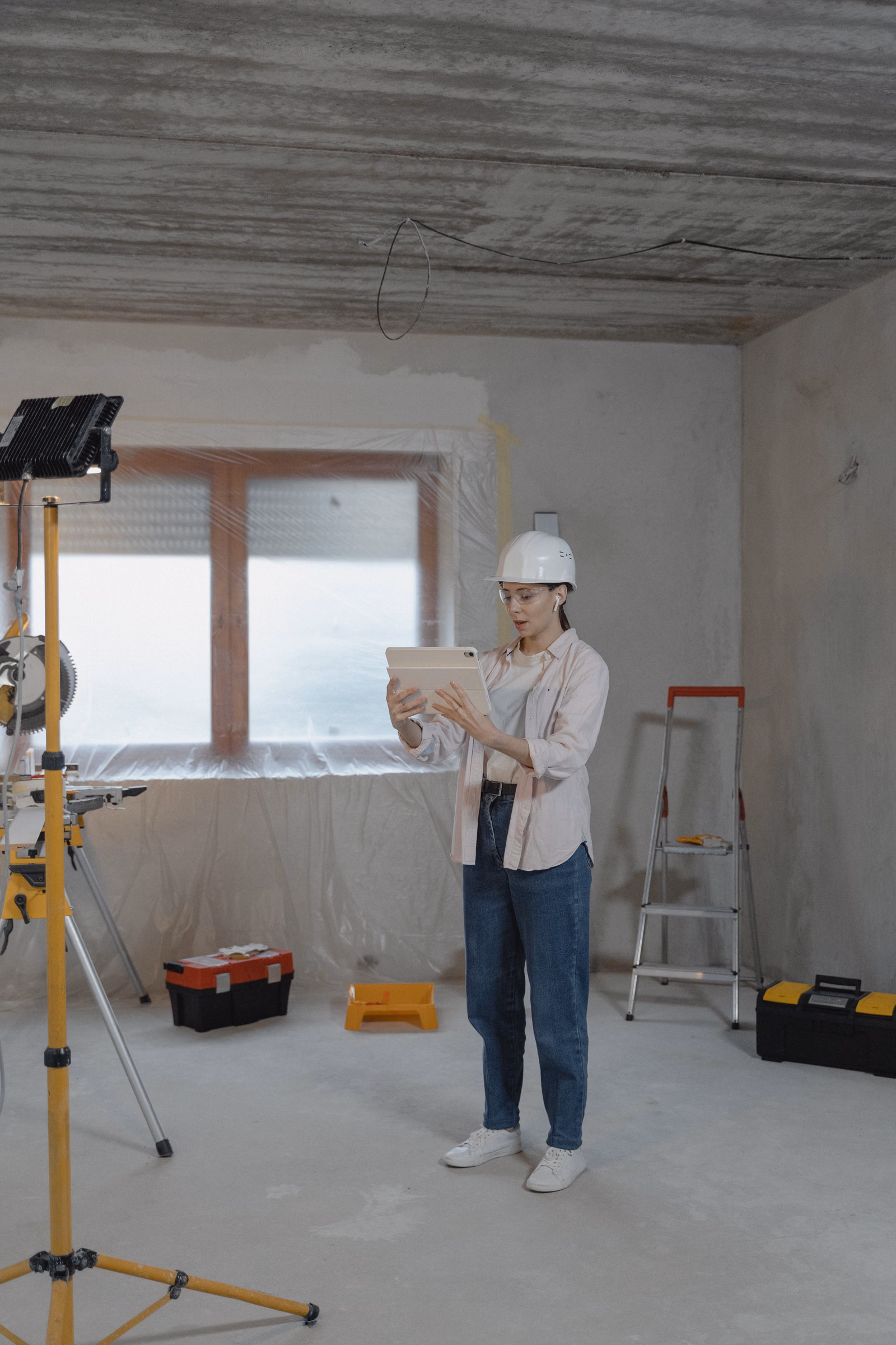 Profissional com capacete usando tablet durante vistoria em ambiente interno