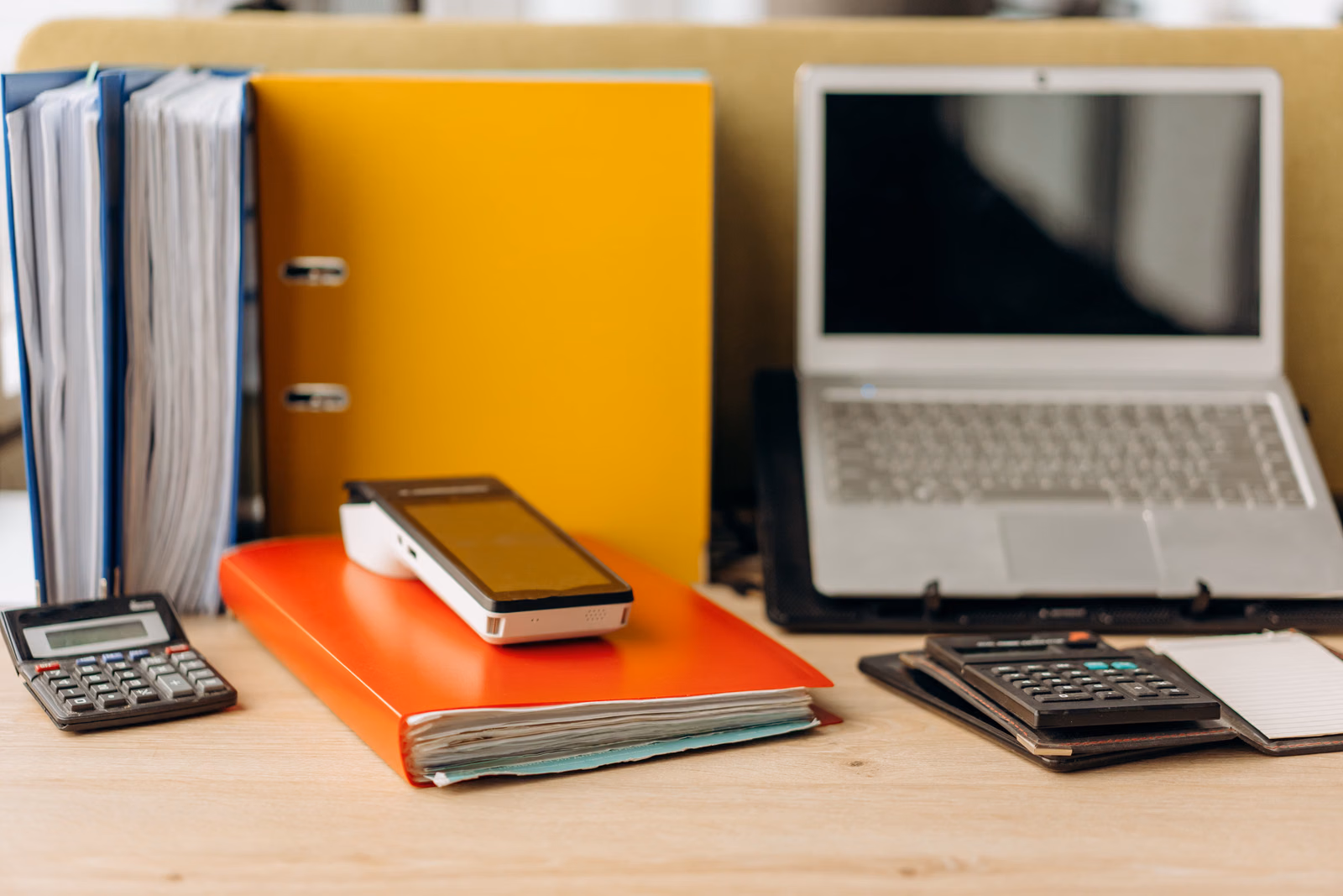 Laptop beside documents and analysis materials on a work desk